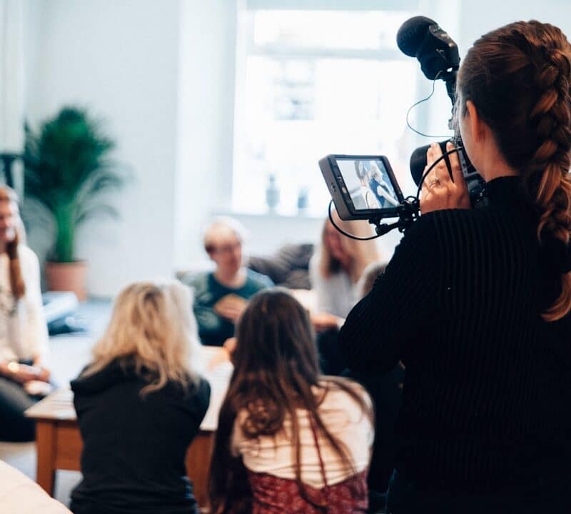 woman holding camera standing near people