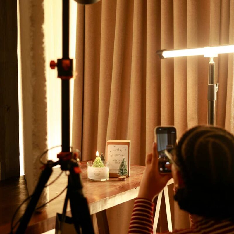 Person photographs a small candle on a table.