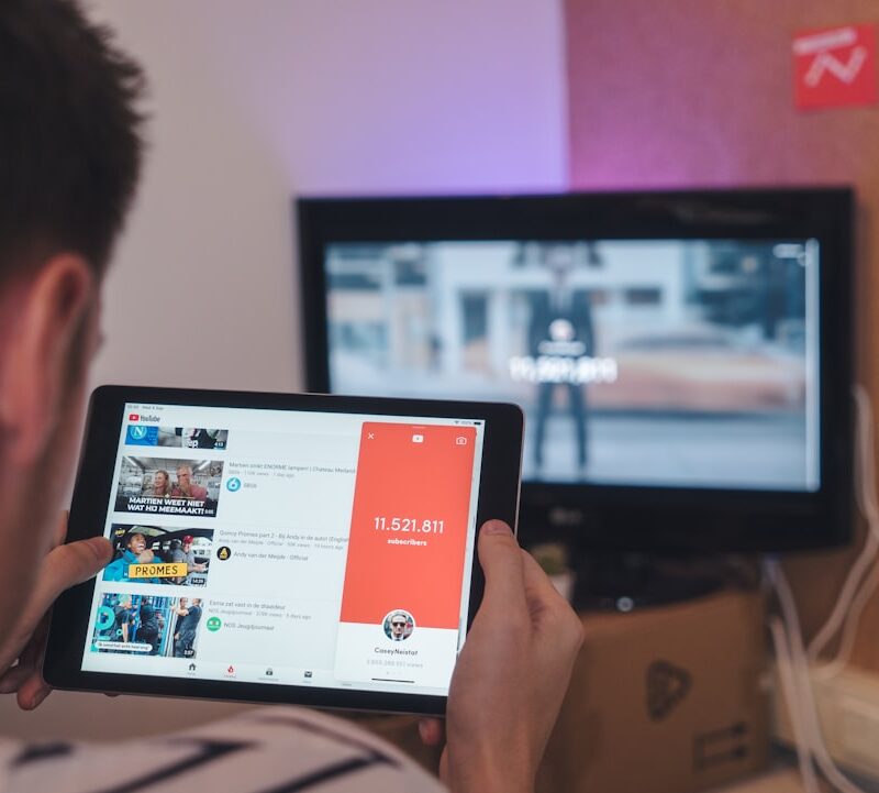 man browsing tablet sitting in front of TV