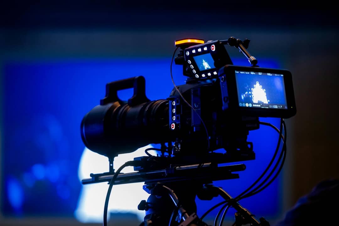 Professional video camera on tripod with blue background
