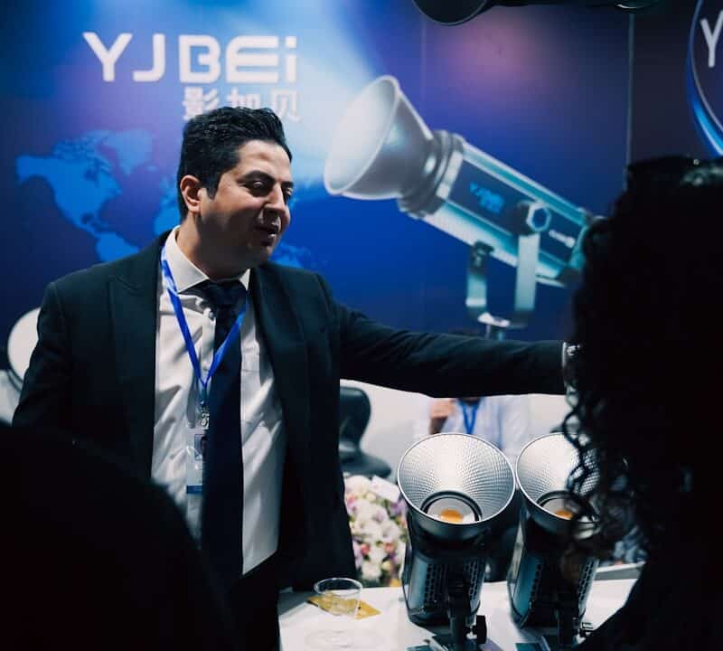 Man in suit presenting equipment at a trade show.