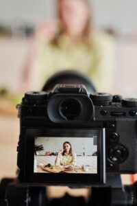 A woman in the background blurred out with the focus on the production camera filming her