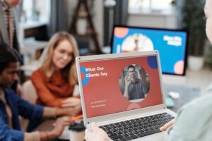 Focus on a laptop with a slide up that says "What Our Clients Say" with a woman in the background