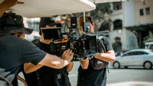 Three video production crew members setting up a professional video camera