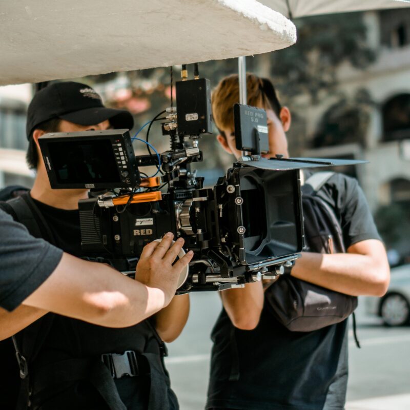 Three video production crew members setting up a professional video camera