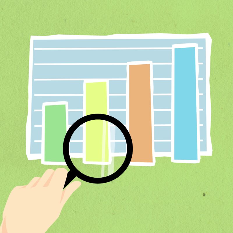 Hand holding a magnifying glass hovering over a bar graph